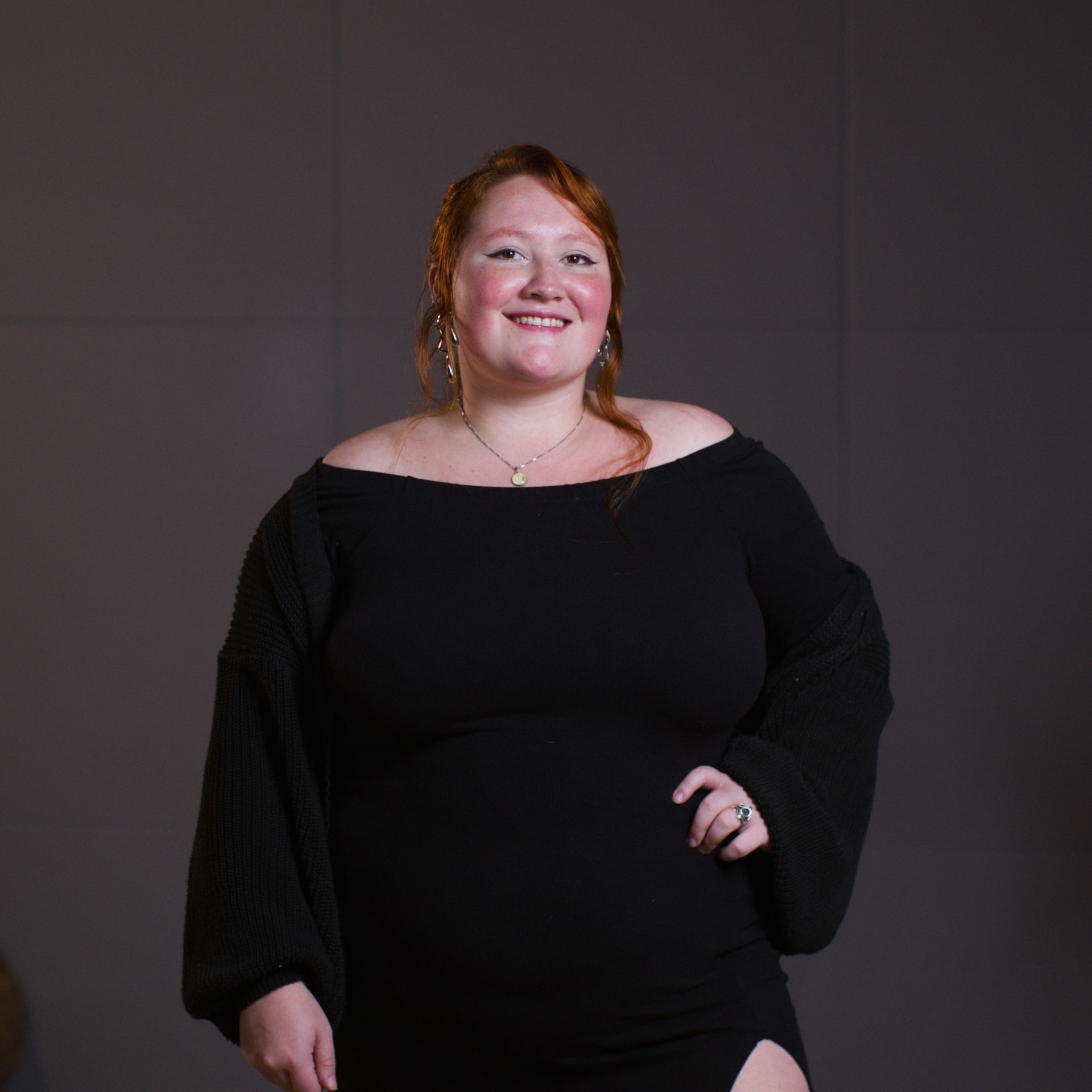 Portrait of Marina Alves smiling, wearing a black top in front of a dark grey studio background